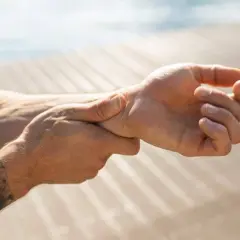 Mann hält sich das Handgelenk, da er Schmerzen im Handgelenk hat.
