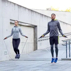 Ein Mann und eine Frau springen Seil. Sie trainieren draußen und zeigen, wie effektiv ist seilspringen für die Fitness.