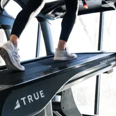 Beine trainieren auf einem Laufband mit Steigung. Das incline walking fordert die Muskulatur.