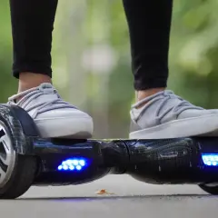 Person fährt Hoverboard mit leuchtenden blauen Lichtern. Die Frage "wie lange braucht ein Hoverboard zum laden?" beschäftigt viele Nutzer.