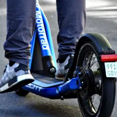 Ein e scooter fahrer auf einem blauen Roller mit dem Schriftzug "Motorrad" und einem Kennzeichen.