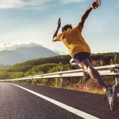 Läufer auf einer Straße, der sich fragt, wie wird man schneller. Bergige Landschaft im Hintergrund.