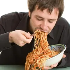 Mann isst genüsslich eine riesige Portion Spaghetti mit Tomatensoße. Perfekt für das Carb Loading vor dem Wettkampf!