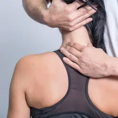 Hände massieren den Nacken einer Frau, die unter nackenschmerzen nach dem schlafen leidet.
