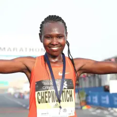 Ruth Chepngetich feiert ihren Sieg beim Dubai Marathon, die Arme erhoben und die Daumen nach oben.