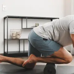 Mann massiert mit Foam Roller seinen vorderen Schienbeinmuskel, um Schmerzen zu lindern.