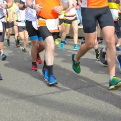 Läufer im Halbmarathon kämpfen um die beste Zeit. Bunte Laufschuhe und kurze Hosen dominieren das Bild.