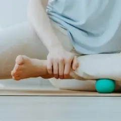 Person löst Verspannungen an den Beinen mit Bällen, um myofasziale Ketten zu lockern.