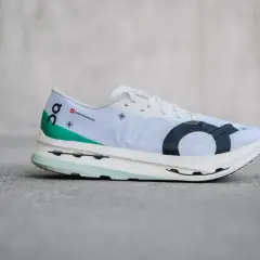 Weißer Laufschuh, On Cloudboom Echo 3, mit grünen Akzenten und schwarzem Logo.