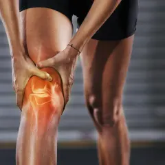 Läufer hält schmerzendes Knie, das rot leuchtet. Knieschmerzen nach Joggen sind ein häufiges Problem.