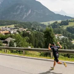 Läufer beim Pitztal Marathon mit Daumen hoch, im Hintergrund ein malerisches Bergdorf.