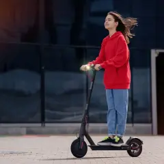 Junge Frau auf E-Scooter, genießt die Fahrt. Ab wann darf man E-Roller fahren? Ab 14 Jahren mit Zustimmung der Eltern.