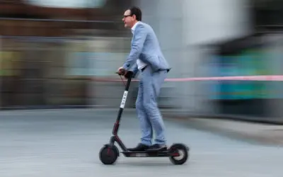 Mann im Anzug fährt mit einem E-Scooter durch Belgien.