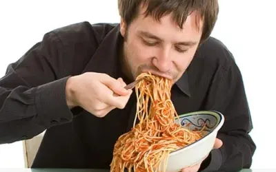 Mann isst genüsslich eine riesige Portion Spaghetti mit Tomatensoße. Perfekt für das Carb Loading vor dem Wettkampf!