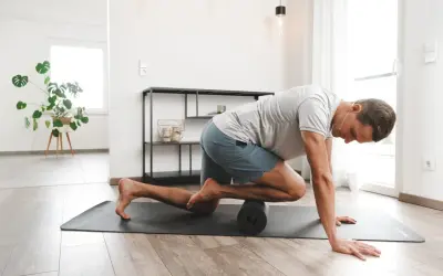 Mann behandelt sein Schienbeinkantensyndrom selbst mit einer Faszienrolle auf einer Matte.