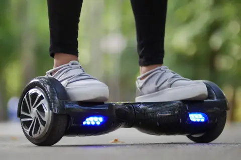 Person fährt Hoverboard mit leuchtenden blauen Lichtern. Die Frage "wie lange braucht ein Hoverboard zum laden?" beschäftigt viele Nutzer.