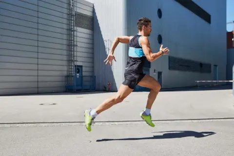 Ein Mann in Sportkleidung läuft dynamisch. Er konzentriert sich darauf, richtig laufen zu lernen, um seine Leistung zu verbessern.
