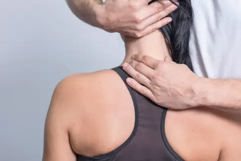 Hände massieren den Nacken einer Frau, die unter nackenschmerzen nach dem schlafen leidet.