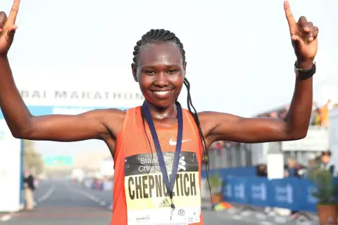 Ruth Chepngetich feiert ihren Sieg beim Dubai Marathon, die Arme erhoben und die Daumen nach oben.