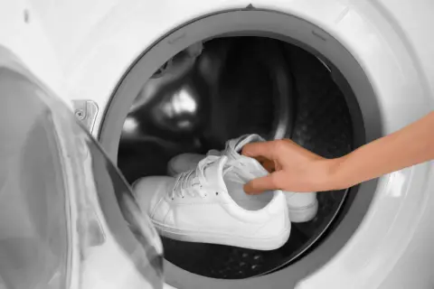 Weiße Laufschuhe werden in eine Waschmaschine gelegt.
