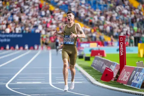 Jakob Ingebrigtsen jubelt nach seinem Weltrekordlauf. Der Athlet rennt auf der Laufbahn, die Zuschauermenge ist im Hintergrund zu sehen.