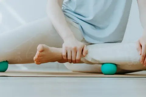 Person löst Verspannungen an den Beinen mit Bällen, um myofasziale Ketten zu lockern.