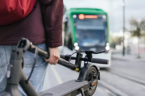 Person mit E-Scooter wartet auf die S-Bahn.