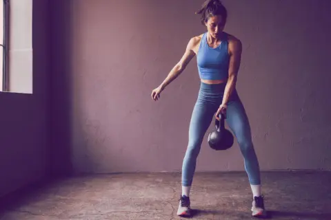 Frau trainiert mit Kettlebell, bereit für die Herausforderung 75 Hard.
