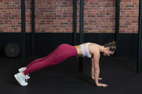 Frau in pinker Sportkleidung macht einen Plank für ihr core workout.