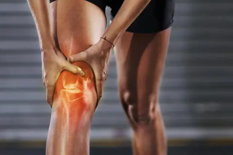 Läufer hält schmerzendes Knie, das rot leuchtet. Knieschmerzen nach Joggen sind ein häufiges Problem.