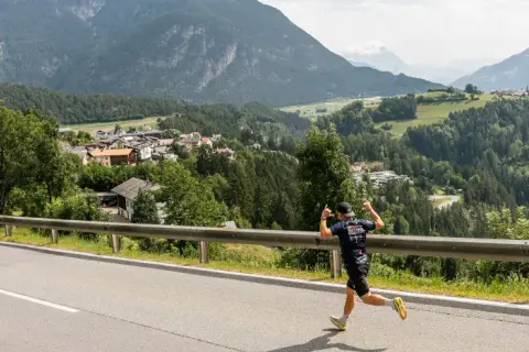 Läufer beim Pitztal Marathon mit Daumen hoch, im Hintergrund ein malerisches Bergdorf.