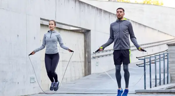 Ein Mann und eine Frau springen Seil. Sie trainieren draußen und zeigen, wie effektiv ist seilspringen für die Fitness.