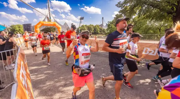 Läufer beim b2run Munich, eine Frau gibt Daumen hoch.