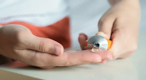 Eine Hand drückt eine Tube aus, um eine klare Salbe auf die andere Hand zu geben. Hilft bei Muskelkater, z.B. mit Ibuprofen.