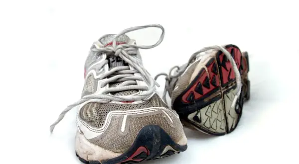 Abgenutzte Laufschuhe auf weißem Hintergrund. Die Sohlen zeigen Verschleiß, was Fragen aufwirft, wie lange halten laufschuhe wirklich?