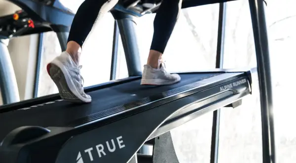 Beine trainieren auf einem Laufband mit Steigung. Das incline walking fordert die Muskulatur.