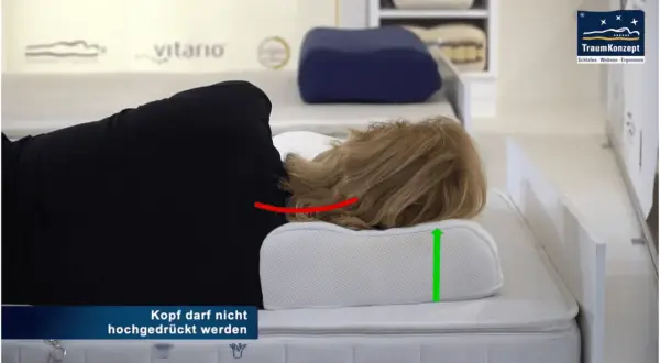 Frau liegt auf einem ergonomischen Kissen, das den Nacken bei HWS-Syndrom stützt. Der Kopf wird nicht hochgedrückt.