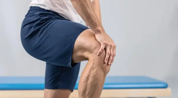 Mann hält schmerzgebeugt sein Knie, nachdem es laut knackte.