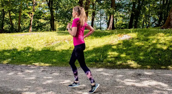Frau im Park beim warm up laufen, genießt die Natur.