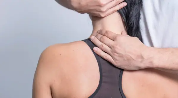 Hände massieren den Nacken einer Frau, die unter nackenschmerzen nach dem schlafen leidet.