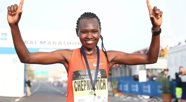 Ruth Chepngetich feiert ihren Sieg beim Dubai Marathon, die Arme erhoben und die Daumen nach oben.