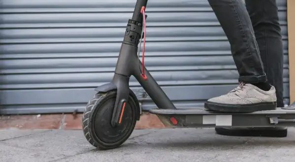 Ein Mann steht auf einem E-Scooter. Die Frage, ob man einen E-Scooter orten kann, beschäftigt viele Nutzer.