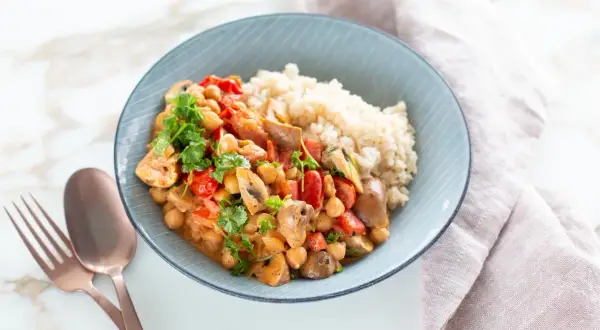 Ein köstliches, proteinreiches Abendessen: Kichererbsen-Curry mit Pilzen, Tomaten und Reis, garniert mit frischer Petersilie.