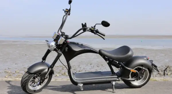 Schwarzer E-Scooter im Chopper-Stil am Strand der Niederlande. Ab wann darf man damit fahren?