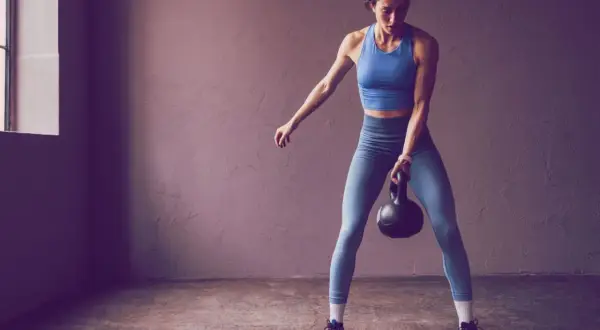 Frau trainiert mit Kettlebell, bereit für die Herausforderung 75 Hard.