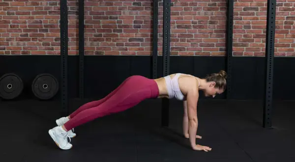 Frau in pinker Sportkleidung macht einen Plank für ihr core workout.