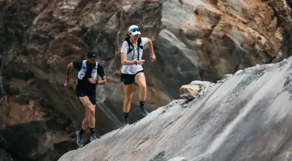 Zwei Läufer meistern einen steilen, felsigen Hang. Sie sind Teil eines Ultramarathons, einer extremen Laufdisziplin.