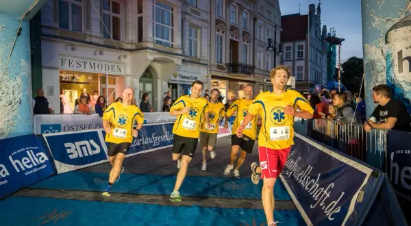 Läufer im Ziel beim hella marathon rostock. Gelbe Trikots mit "Ambulanz Millich" und Startnummern.