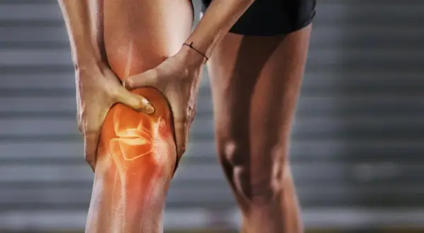 Läufer hält schmerzendes Knie, das rot leuchtet. Knieschmerzen nach Joggen sind ein häufiges Problem.
