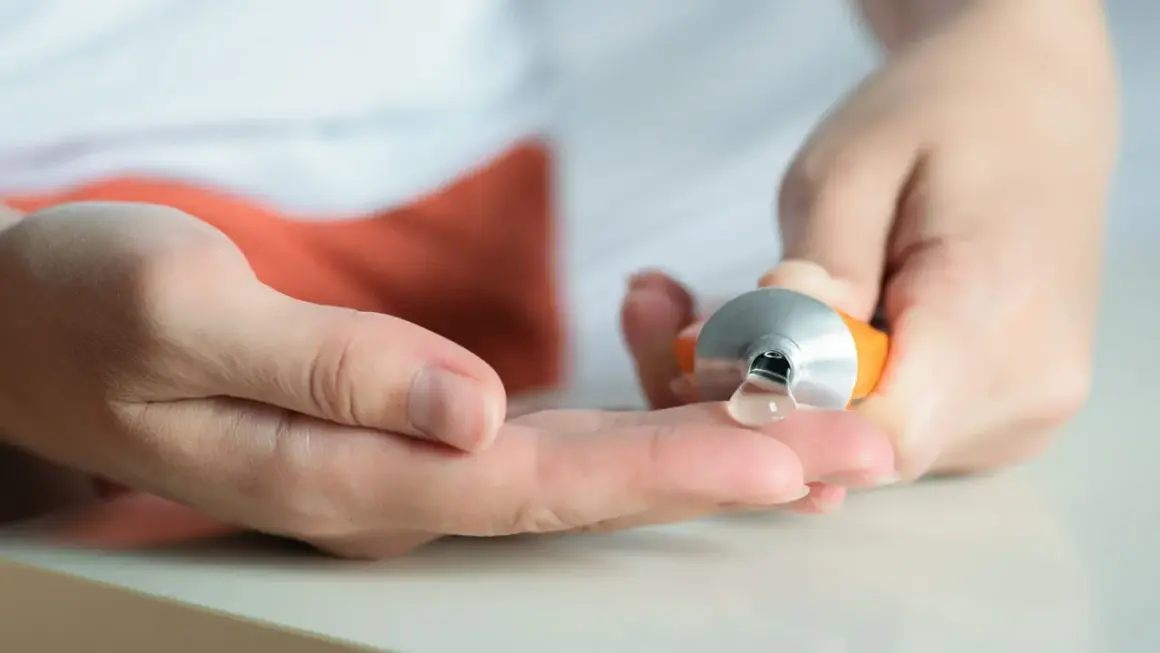 Eine Hand drückt eine Tube aus, um eine klare Salbe auf die andere Hand zu geben. Hilft bei Muskelkater, z.B. mit Ibuprofen.